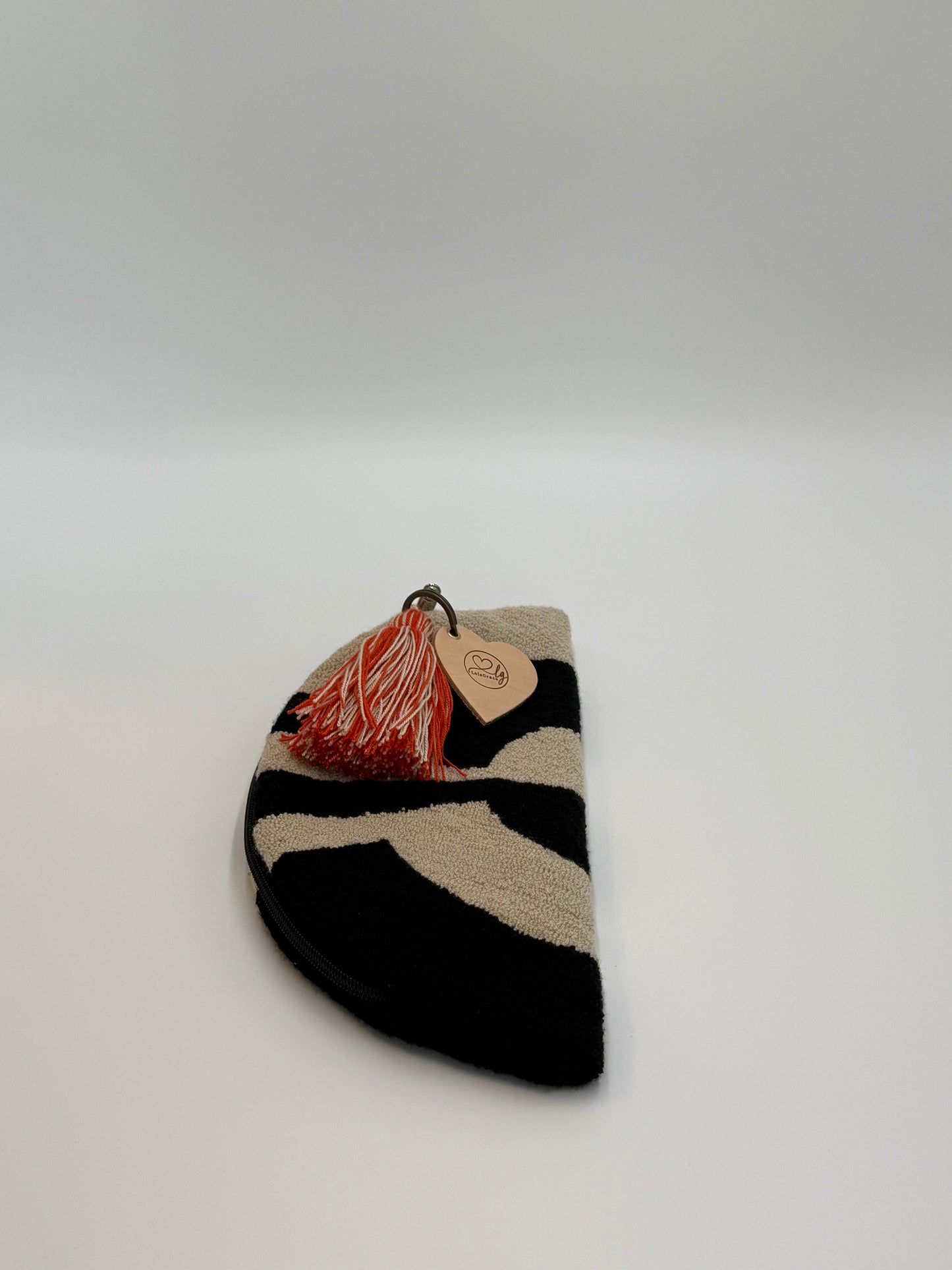 Compacte Wayuu clutch Aura met verfijnd weefwerk en speelse kwast in warme tinten