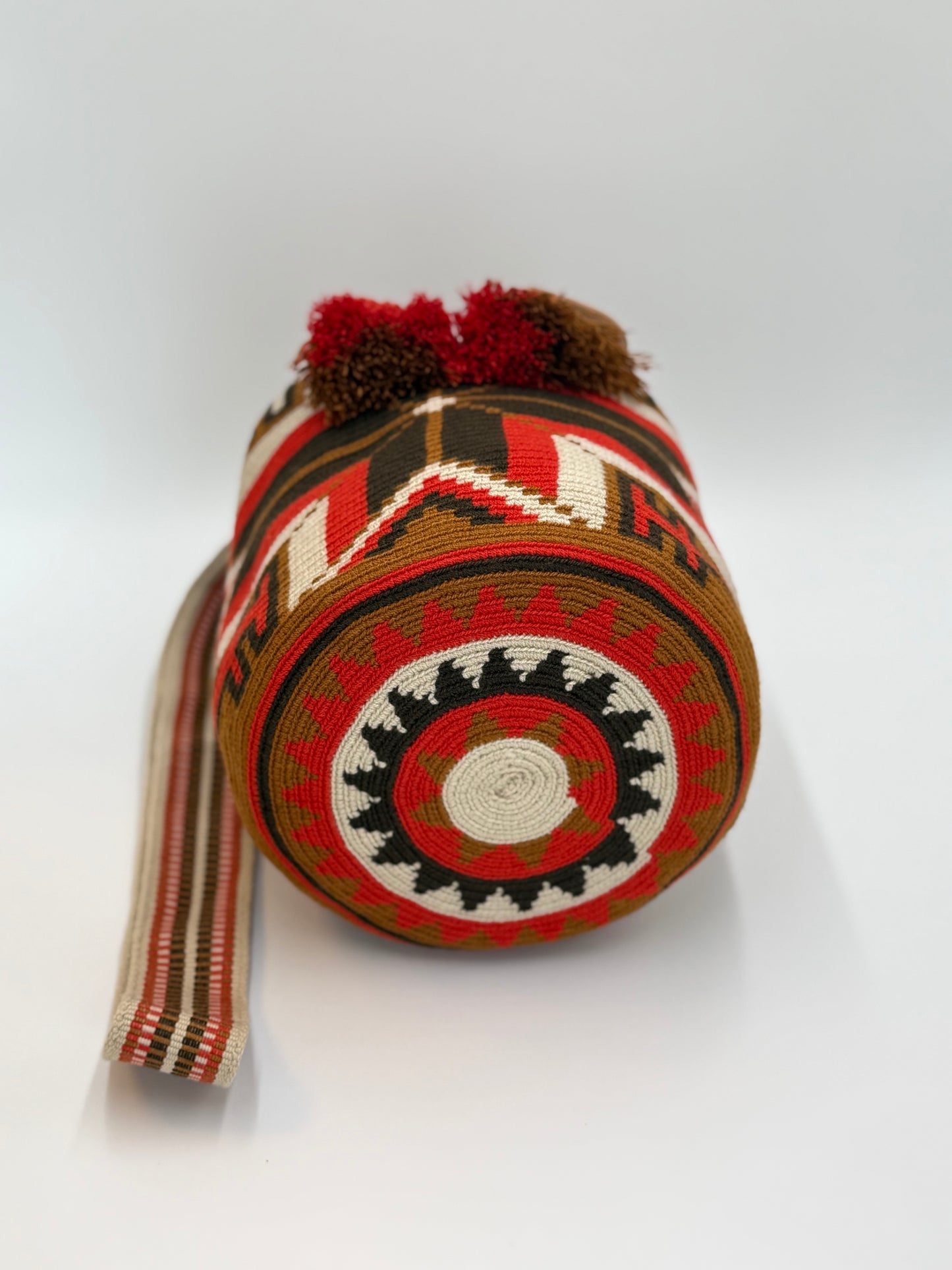 Ronde bodem van Wayuu tas Leidy met krachtig geometrisch design in warme rood- en aardetinten