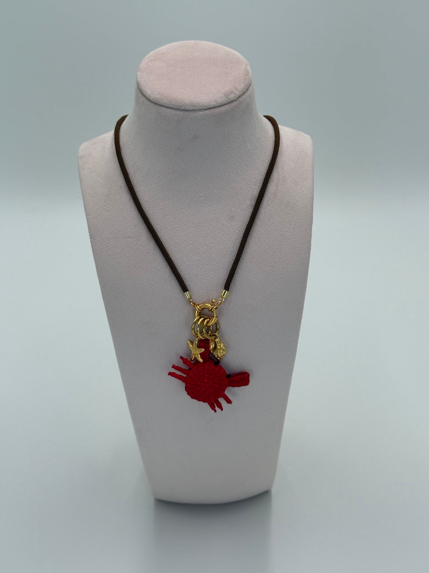 Handgemaakte ketting van gedraaid nylon met 24 karaat vergulde accenten, een krab van Werregue-palm en vergulde zeester- en schelpbedels
