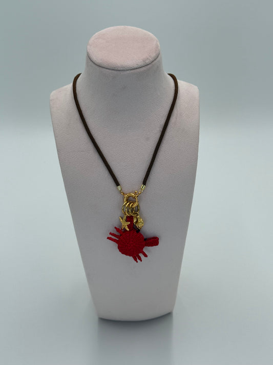 Handgemaakte ketting van gedraaid nylon met 24 karaat vergulde accenten, een krab van Werregue-palm en vergulde zeester- en schelpbedels
