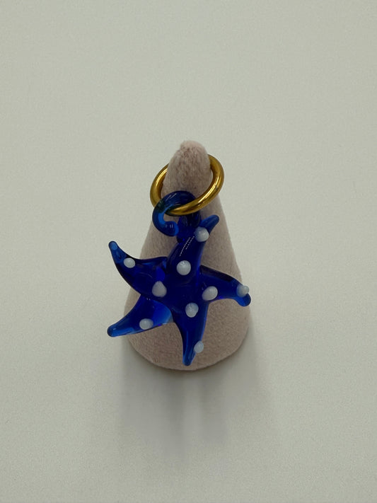 Handgemaakte blauwe glazen zeester kettingbedel met witte stippen, bevestigd aan een bronzen ring verguld met 24 karaat goud