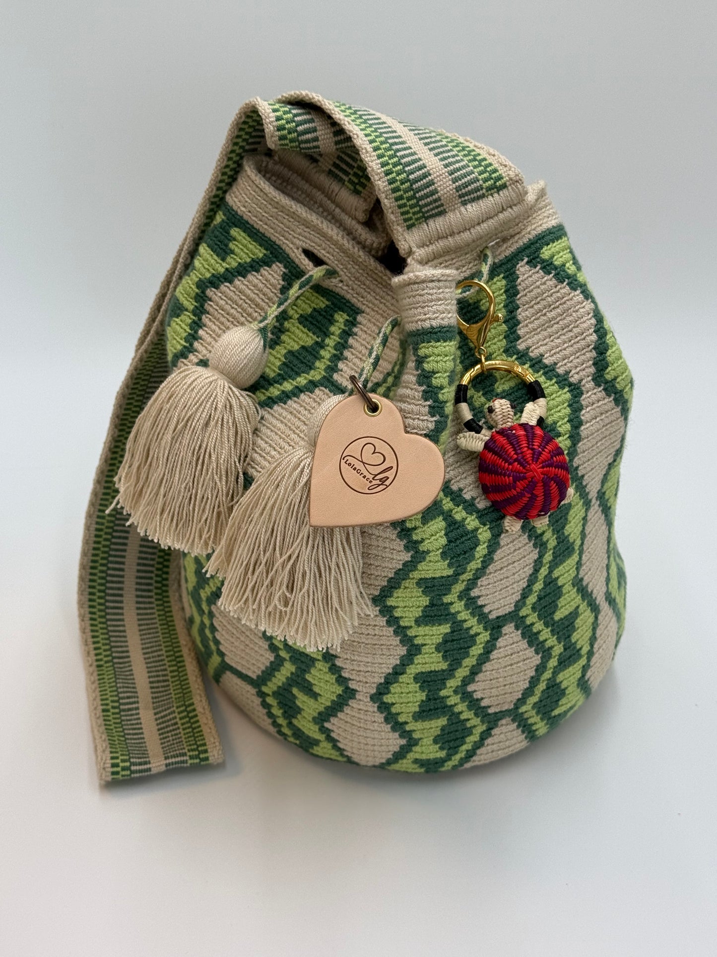 Handgemaakte LolaGrace schildpad tasbedel van Werregue-palm met brons en 24-karaat vergulde details bevestigd aan een Wayuu mochila tas.