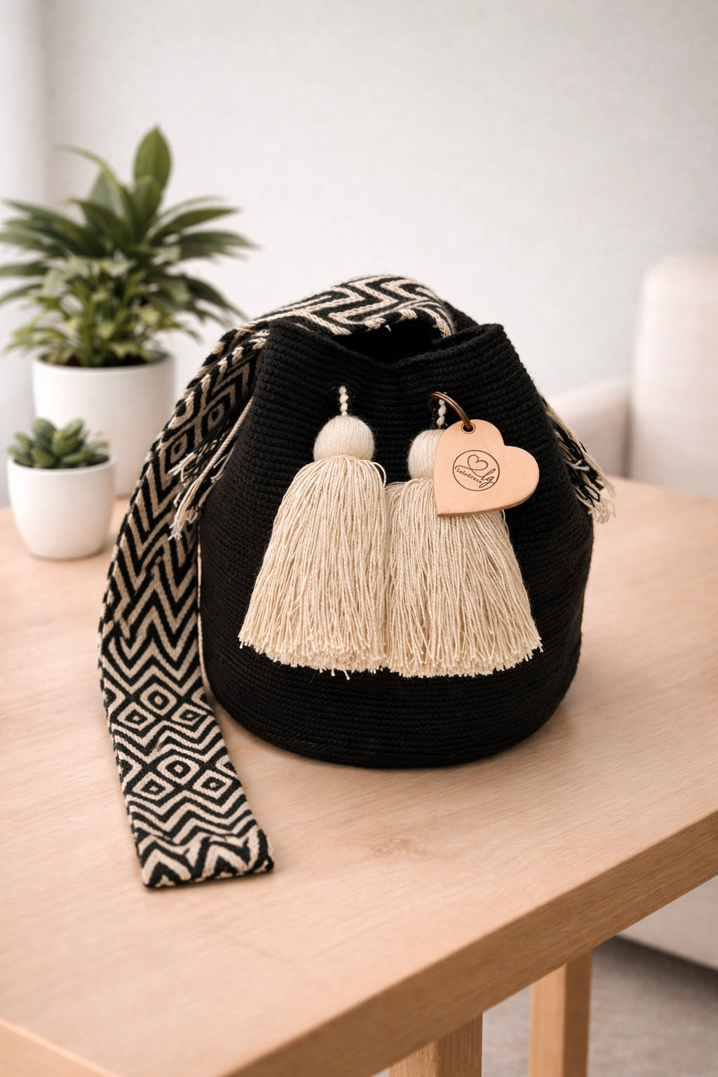 Esmeralda large Wayuu mochila tas van LolaGrace handgemaakt in Colombia met zwart design op houten tafel in lichte interieursetting