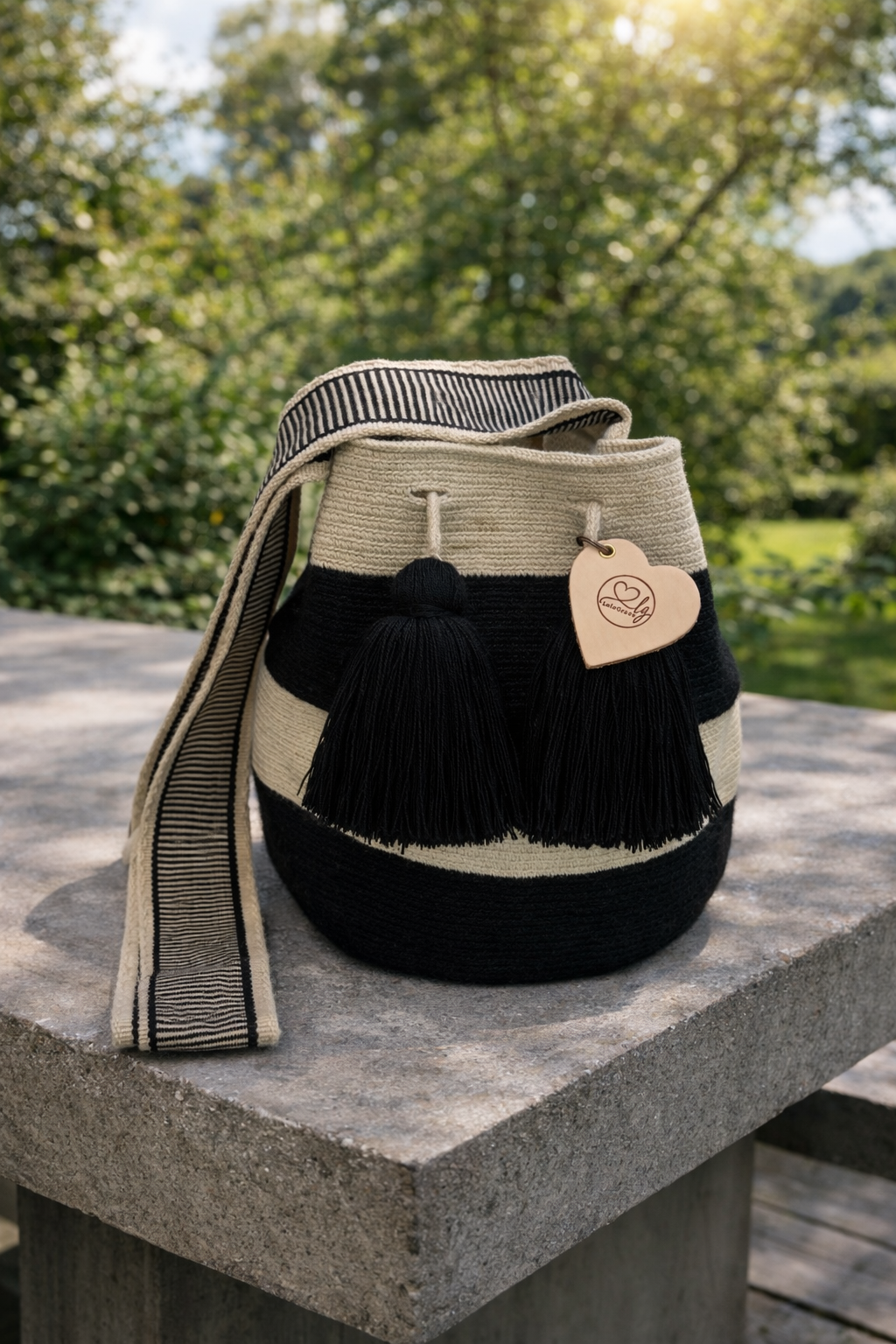 Handgemaakte Wayuu tas Isabela Large van LolaGrace in zwart en crème op betonnen tafel in de tuin, artisan Wayuu bag uit Colombia.
