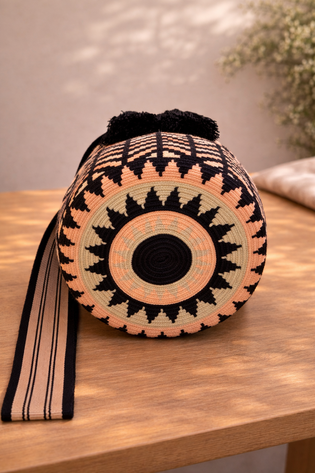 Karen Large Wayuu mochila tas van LolaGrace op houten tafel, handgemaakt in Colombia met zwart, perzik en crème geometrisch patroon.