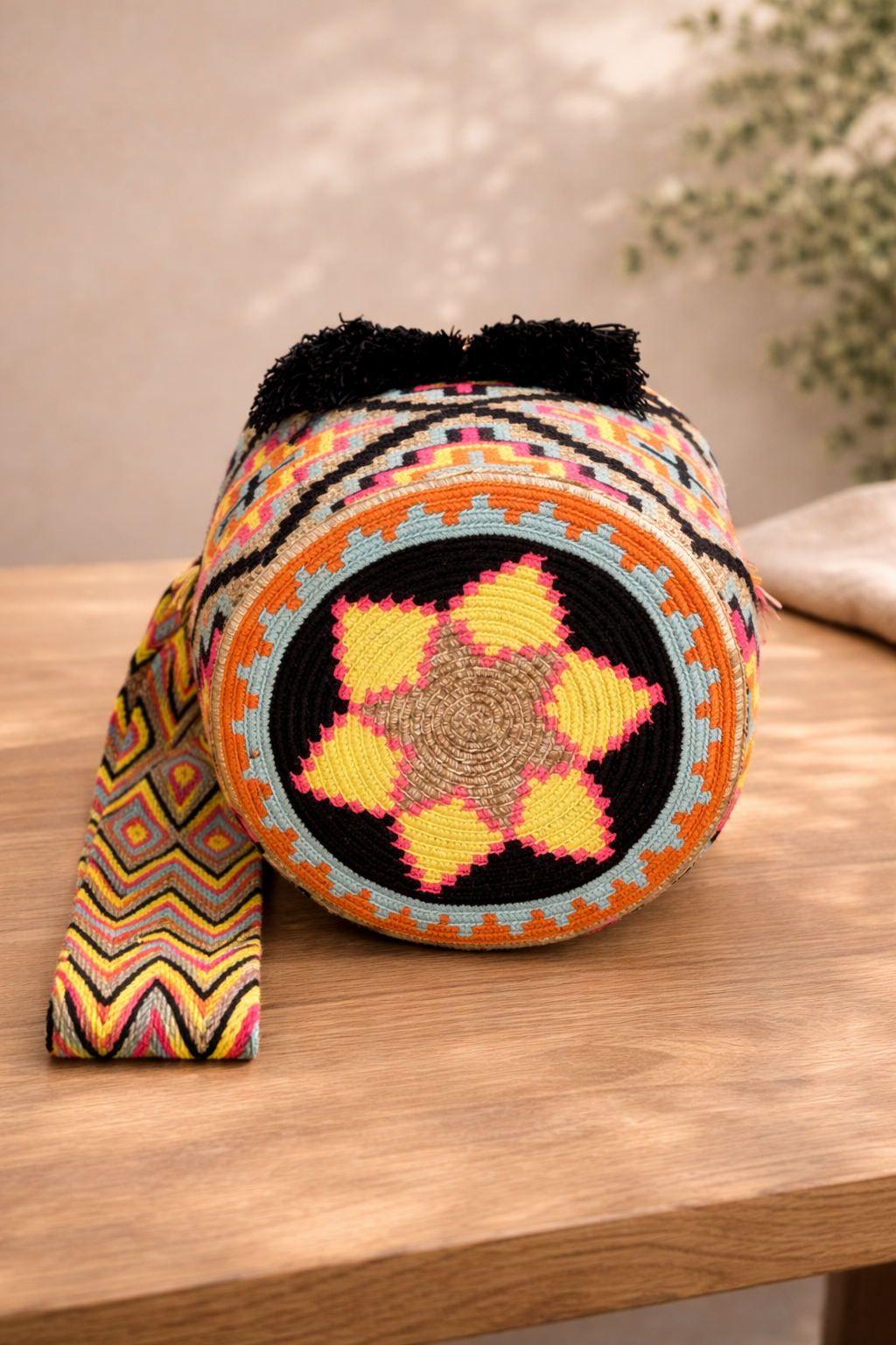 Teresa Large Wayuu mochila tas van LolaGrace op houten tafel, handgemaakt door de Wayuu gemeenschap in La Guajira, Colombia.