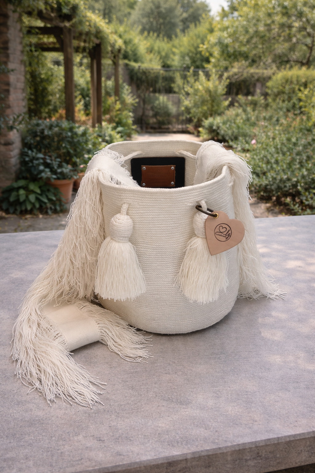 Elegante Wayuu tas Yamile in wit, stijlvol geplaatst in een rustige groene buitenomgeving