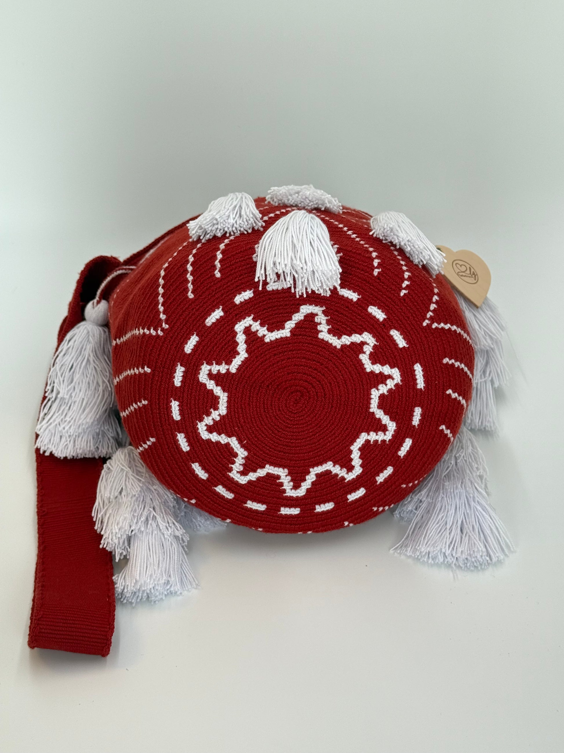 Onderkant van Ana Sofía medium Wayuu tas van LolaGrace handgemaakt in Colombia met rood patroon en witte kwasten