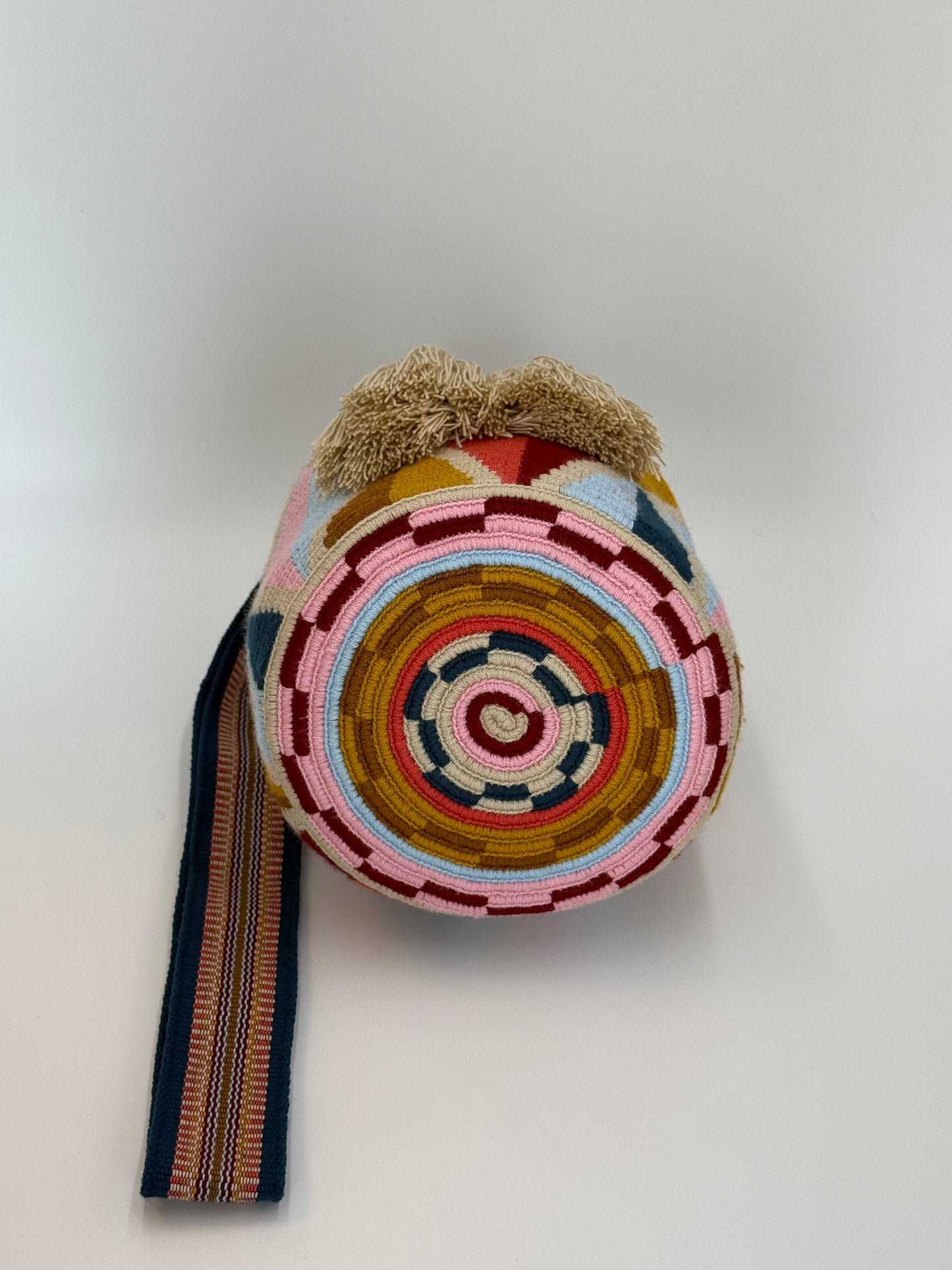 Onderkant van handgemaakte Wayuu tas Carmen Medium van LolaGrace met kleurrijk rond geweven patroon in roze, oker, blauw en crème, traditioneel vakmanschap uit Colombia.