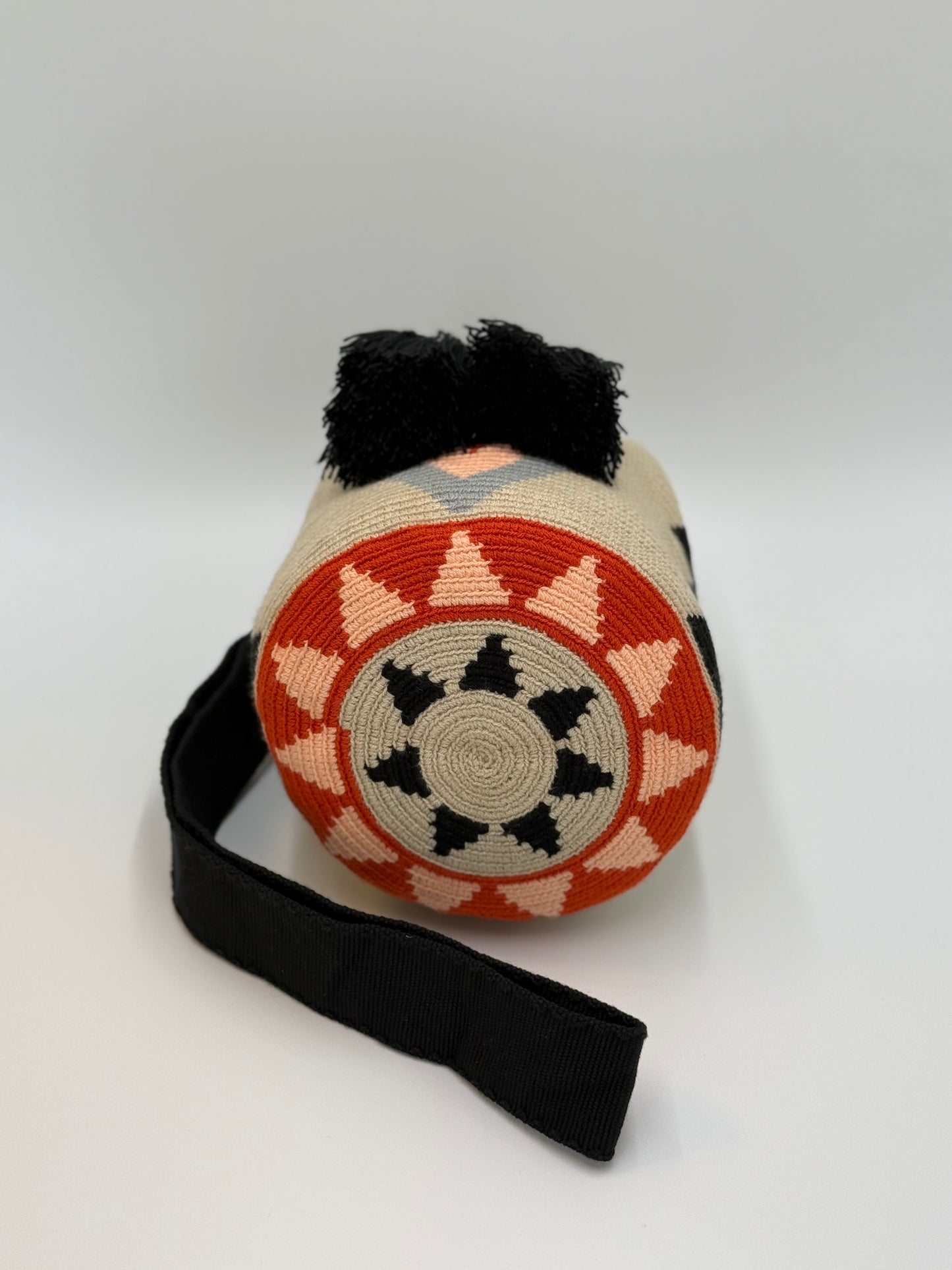 Ronde bodem van Wayuu tas Nayibe met opvallend geometrisch motief in zwart, zand en terracotta tinten