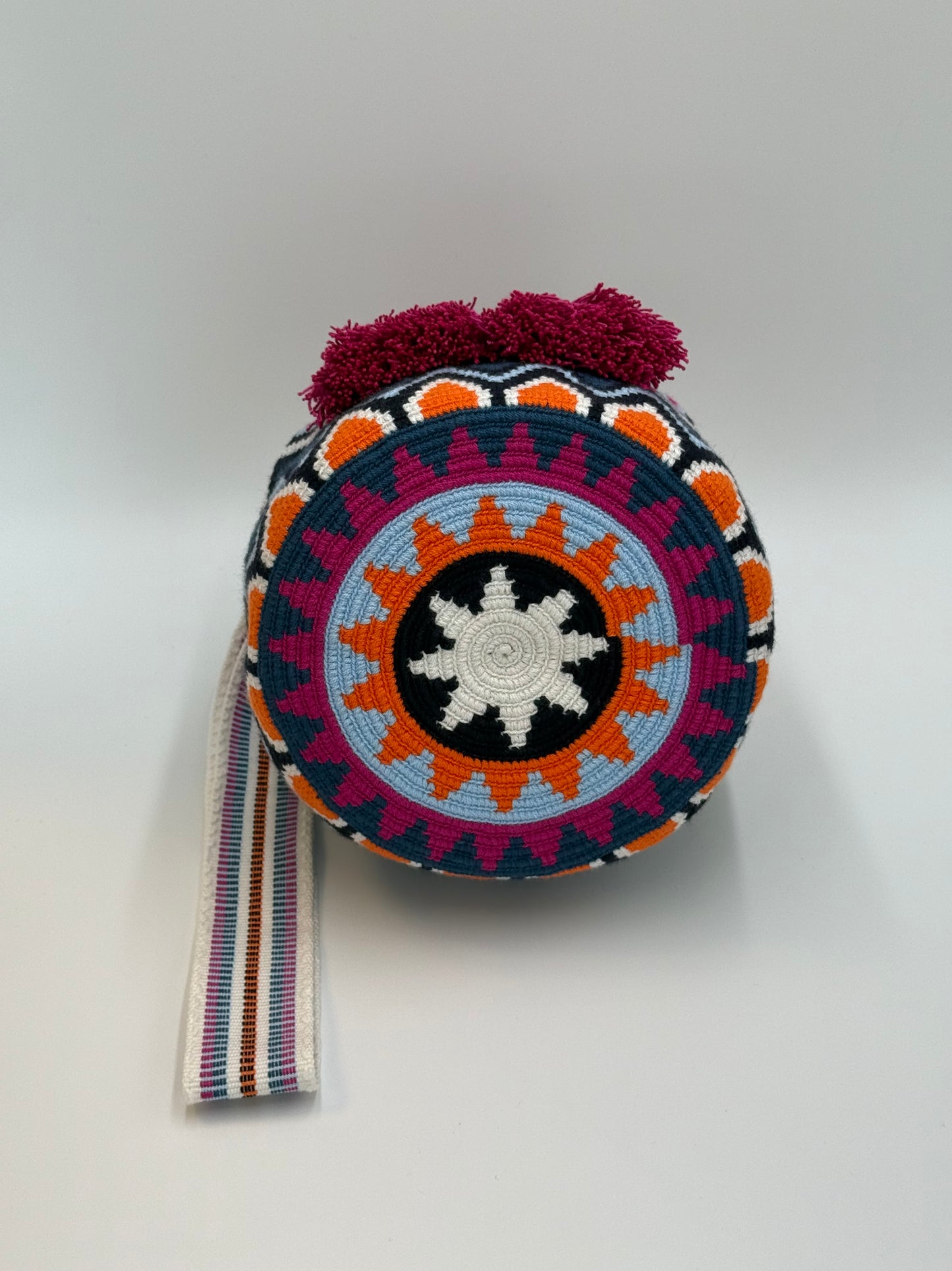 Onderkant van Rosaura Medium Wayuu mochila tas met traditioneel Wayuu patroon in zwart, oranje, blauw en roze, handgemaakt in Colombia.