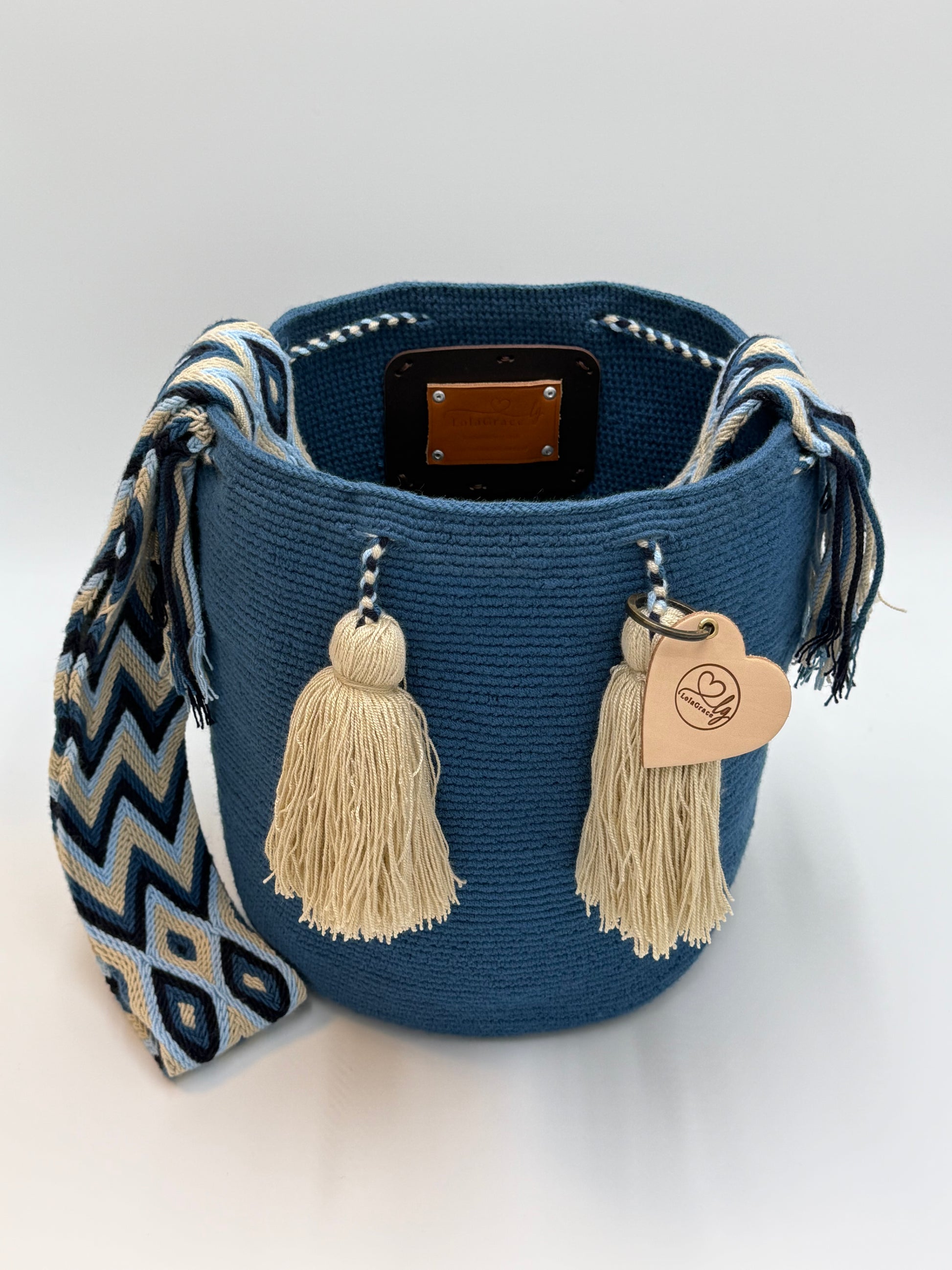 Open Wayuu tas Gabriela María Large van LolaGrace met trekkoordsluiting, beige kwastjes en handgeweven schouderband in blauw en crème.