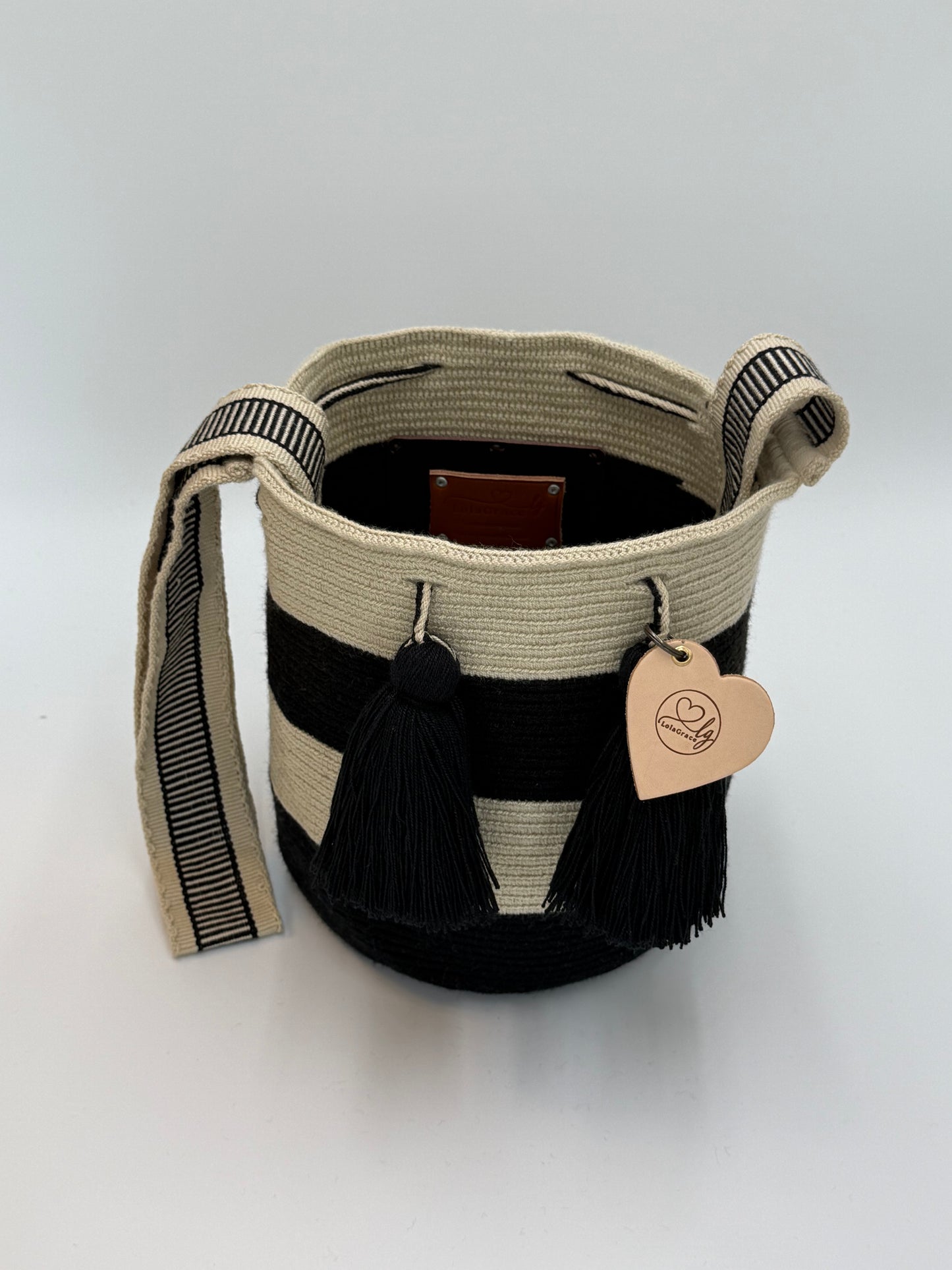 Open handgemaakte Luna Medium Wayuu tas van LolaGrace met zwart-crème strepen, zwarte kwastjes en geweven schouderband.