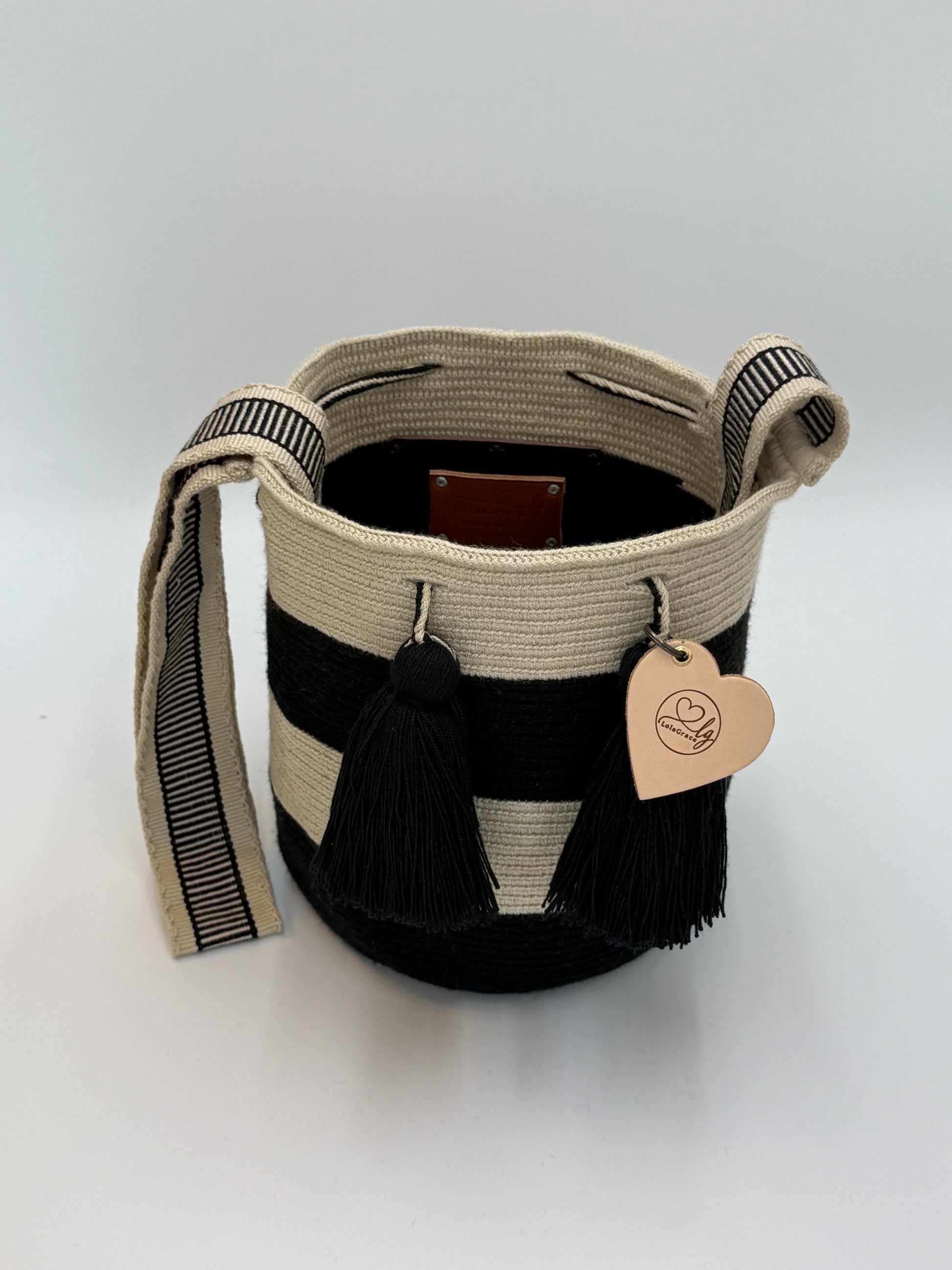Open handgemaakte Luna Medium Wayuu tas van LolaGrace met zwart-crème strepen, zwarte kwastjes en geweven schouderband.