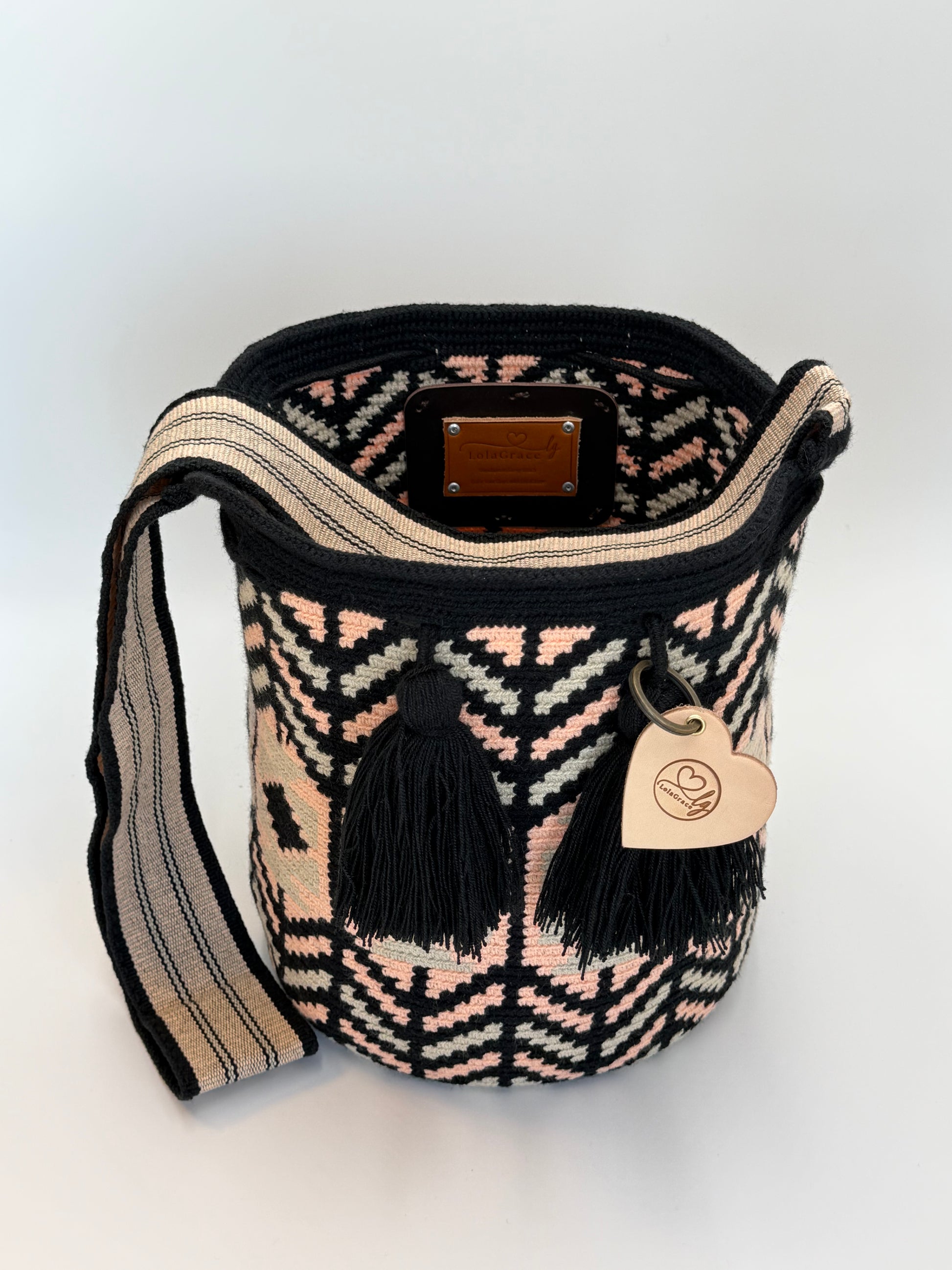 Open Silvia Large Wayuu mochila tas van LolaGrace van bovenaf met handgemaakt patroon in zwart, beige en zachtroze en zwarte kwasten.