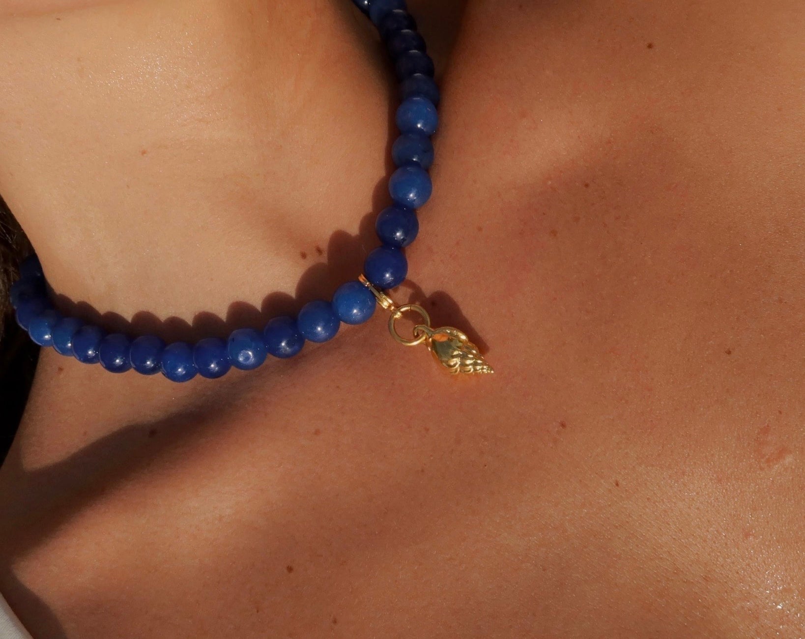 Leticia ketting gedragen model blauwe jade kralen met vergulde schelpbedel brons 24k goud