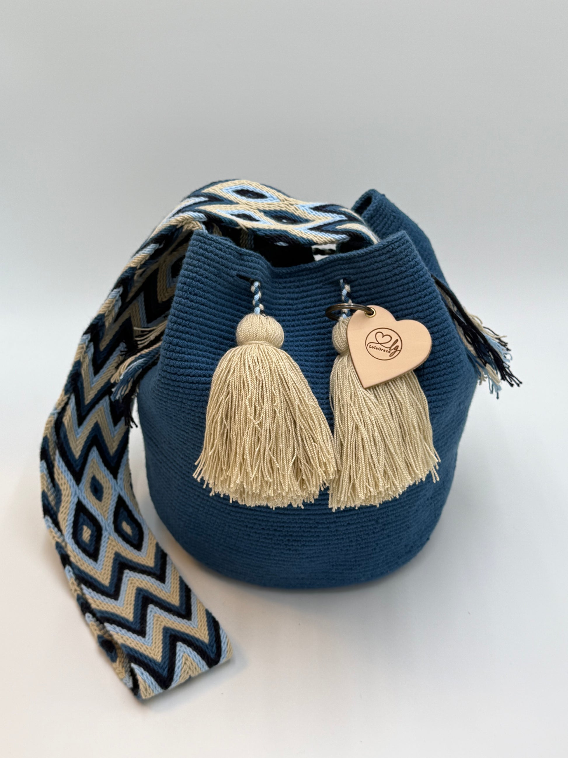 Voorkant van handgemaakte Wayuu tas Gabriela María Large van LolaGrace in diepblauw met beige kwastjes en handgeweven schouderband met geometrisch patroon.