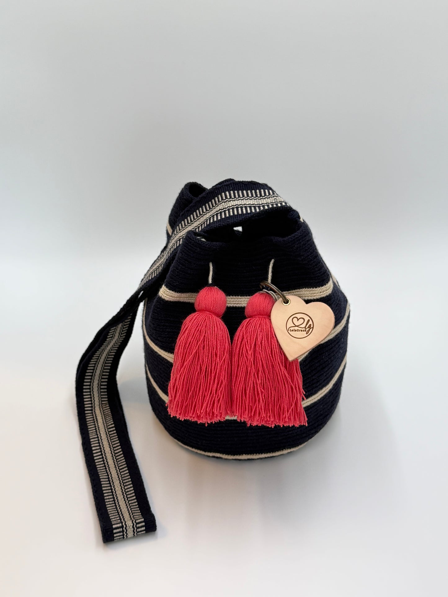Melany Medium Wayuu mochila tas van LolaGrace, handgehaakt door de Wayuu gemeenschap in La Guajira, Colombia, met donkerblauwe strepen, beige details en roze kwasten.