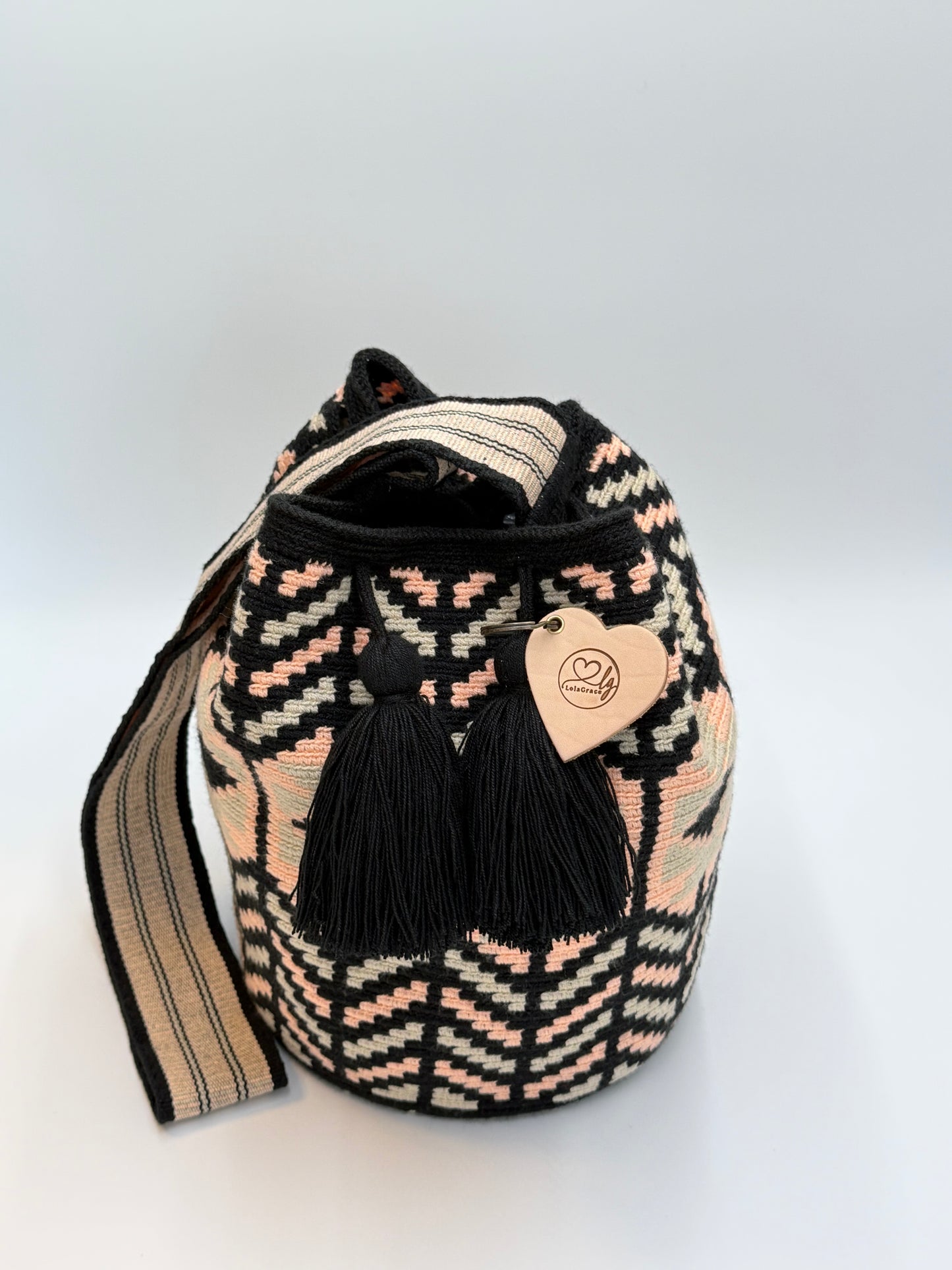 Voorkant van handgemaakte Wayuu tas Olga Large van LolaGrace met zwart, crème en zachtroze geweven patroon en zwarte kwastjes, artisan Wayuu bag uit Colombia.