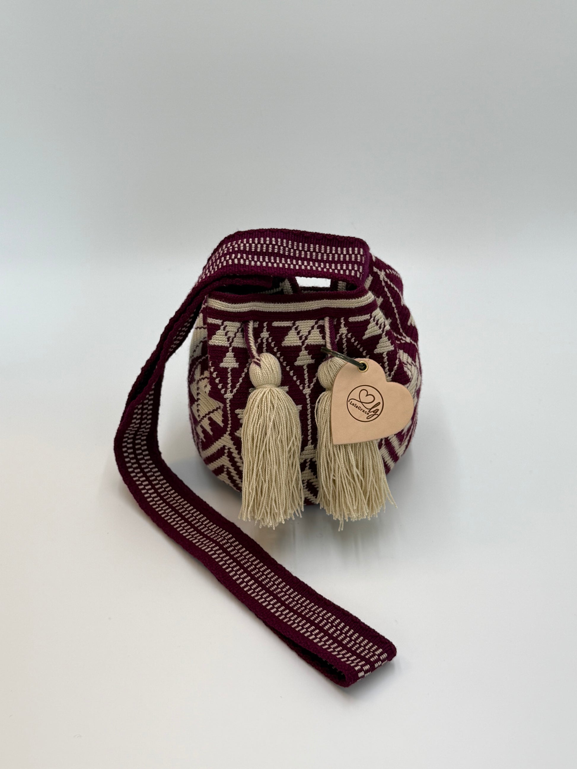 Kleine Wayuu tas Rosa Maria in diep bordeaux met een subtiele paarse ondertoon, afgewerkt met verfijnd patroon en zachte kwastjes