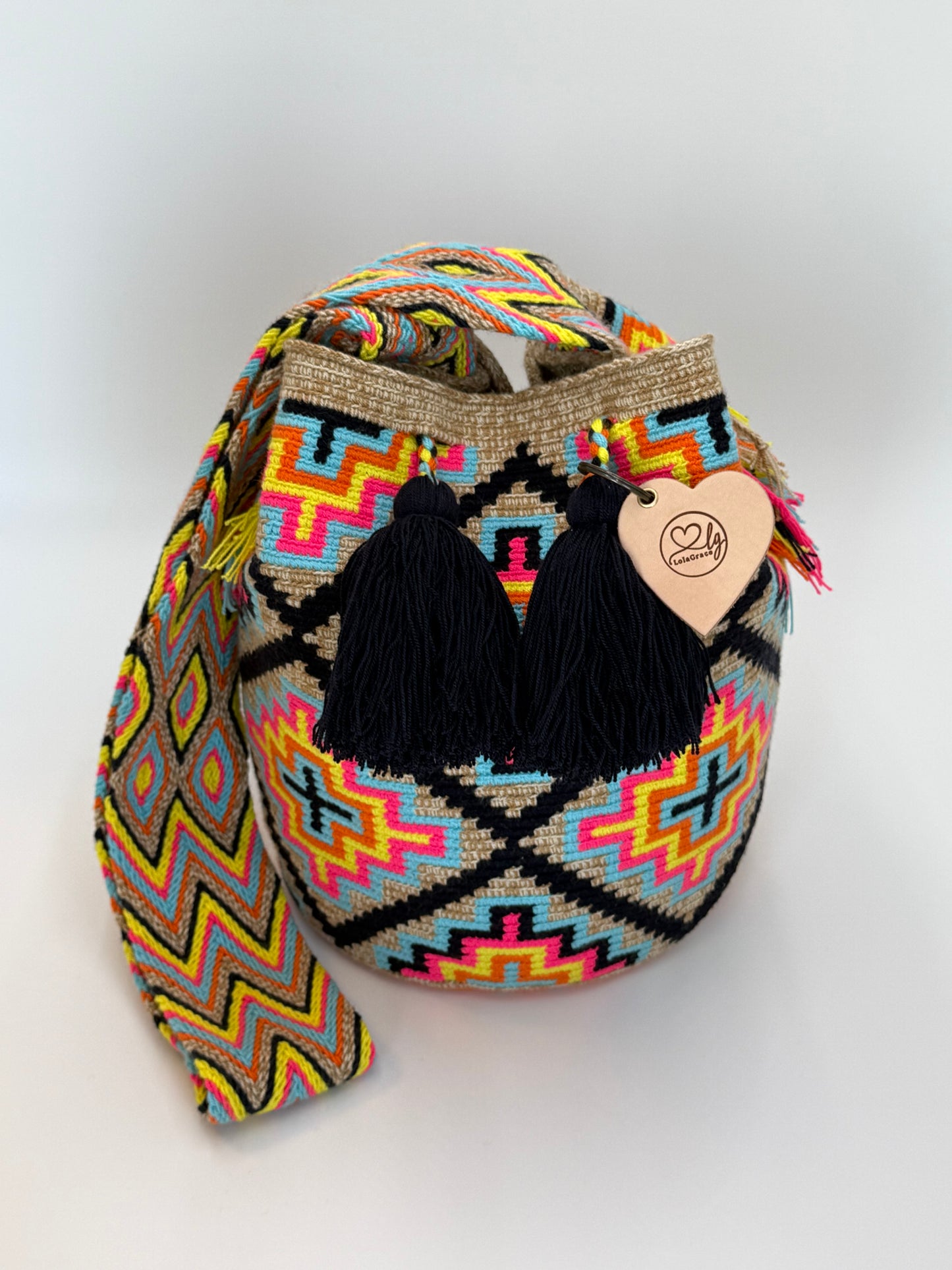Teresa Large Wayuu mochila tas van LolaGrace, handgemaakt door de Wayuu gemeenschap in La Guajira, Colombia, met kleurrijk geometrisch patroon en zwarte kwasten.