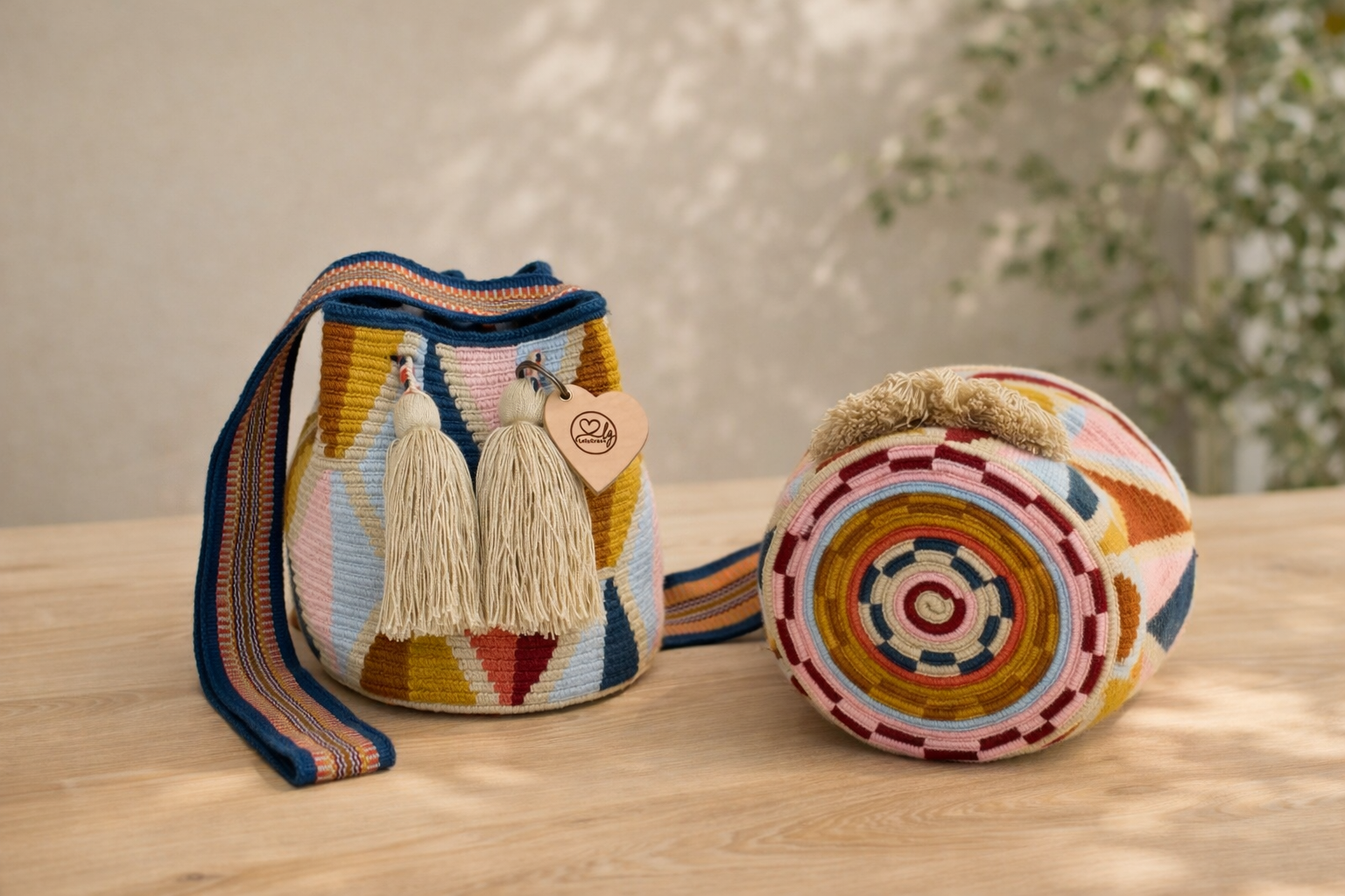 Handgemaakte Wayuu tas Carmen Medium van LolaGrace met kleurrijk geometrisch patroon op houten tafel, artisan Wayuu bag uit Colombia.